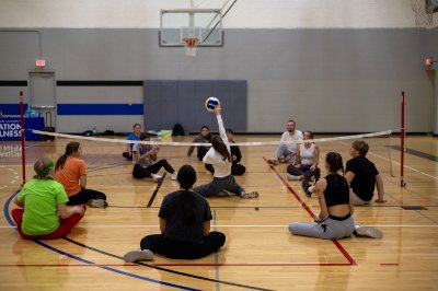 Students participating in seated volleyball at an adaptive intramural sports event.